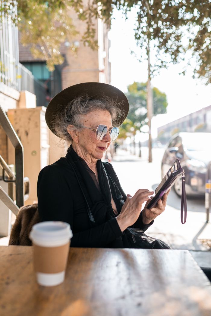 services-02 Stylish senior woman in sunglasses using tablet outdoors at a cafe.