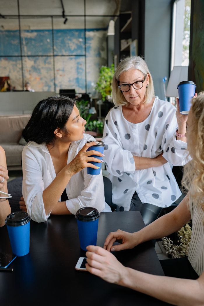 Group of businesswomen having a discussion with coffee cups at a modern office.